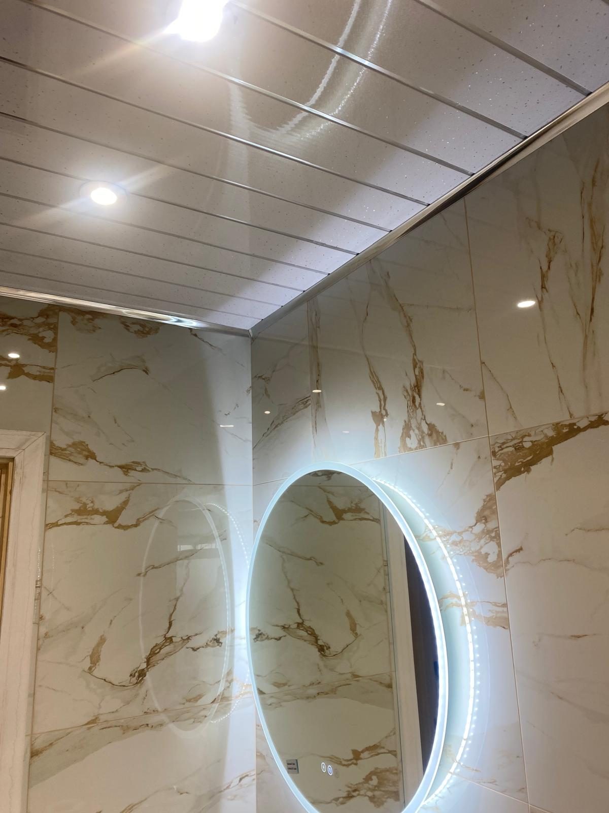 Brushed gold towel radiator against marble-effect wall tiles
